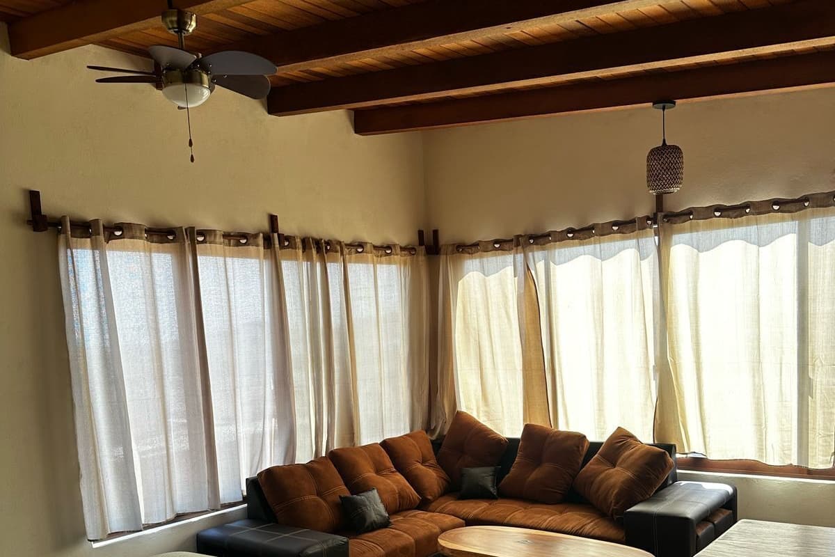 A cozy living room with a sectional sofa, a round coffee table, and a bed with a green quilt.