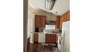 A compact kitchen with wooden cabinets, a dishwasher, and a refrigerator.