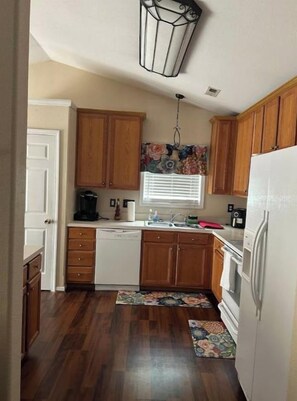 A compact kitchen with wooden cabinets, a dishwasher, and a refrigerator. - Charming 3-bedroom house in Winston-Salem with AC, WiFi (Winston-Salem)