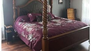 A bedroom with a four-poster bed, a ceiling fan, and a nightstand.