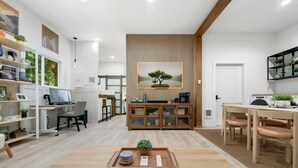 Une pièce moderne et bien éclairée, avec une table à manger en bois, un bureau d’ordinateur et une bibliothèque.