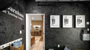 Un intérieur moderne avec un mur foncé, un comptoir d’accueil en bois et des éléments encadrés portant des numéros atomiques et des mots tels que « Vision », « Mentalité » et « Dynamisme ».
