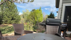 Une terrasse avec des meubles en osier et un barbecue.