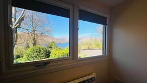A room with two windows overlooking a landscape with trees and a distant view of hills. - The Shack in Fort William (Fort William)