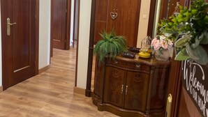 Un pasillo de madera con un espejo grande, un letrero de bienvenida y una planta sobre un mueble de madera.
