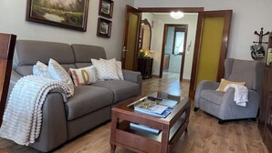 Una sala de estar con sofá, sillón, mesa de centro y candelabro.