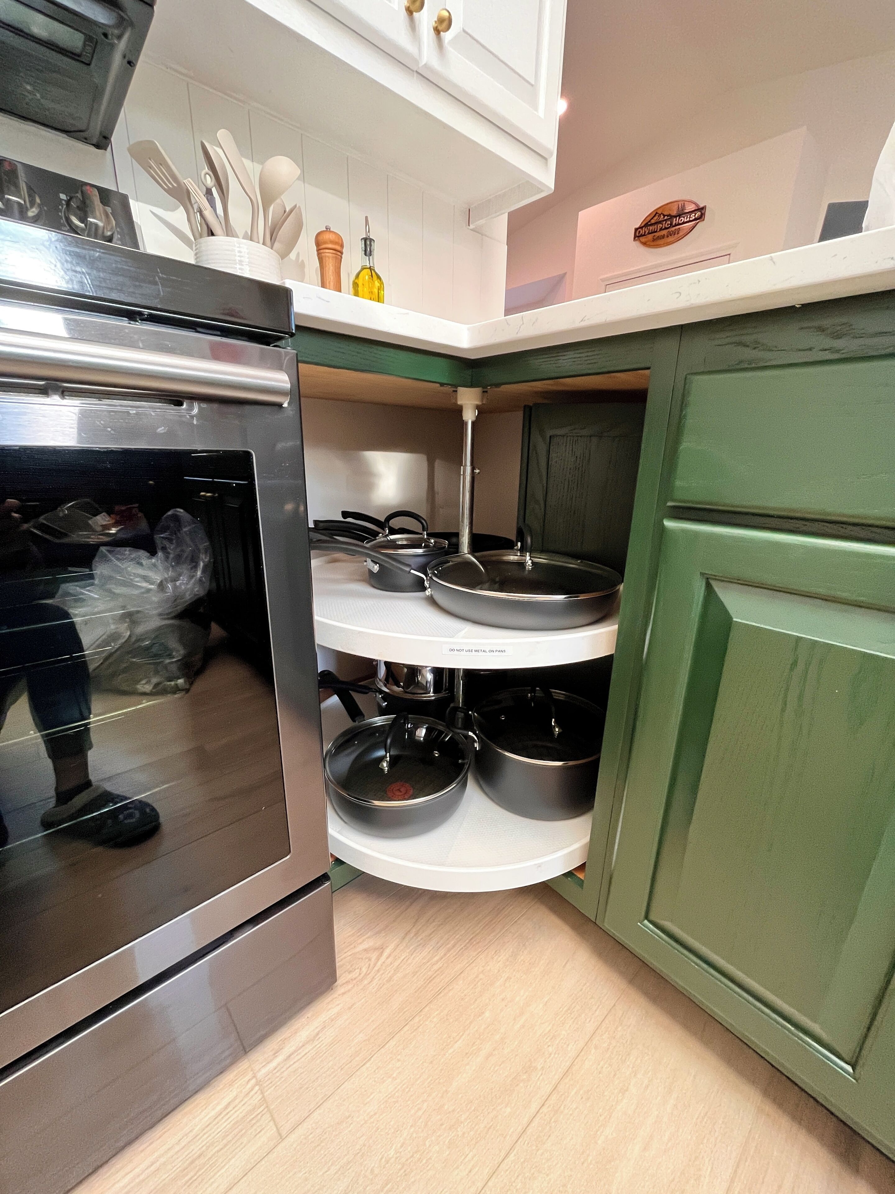 Eine Küche mit eingebautem Ofen, einer Edelstahl-Dunstabzugshaube und einem grünen Schrank.