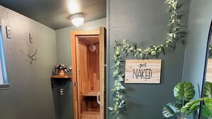A hallway with a wooden bench, a rug, a small table with candles, a potted plant, and a sign that says "GET NAKED". - Olympic House with SAUNA/Rec Room/AC in the Heart of Port Angeles (Port Angeles)