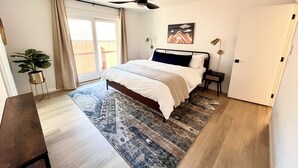A bedroom with a bed, a ceiling fan, a nightstand, a potted plant, and a view of the outside. - Olympic House with SAUNA/Rec Room/AC in the Heart of Port Angeles (Port Angeles)