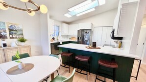 A modern kitchen with white cabinets, a central island with stools, a built-in oven, and a refrigerator. - Olympic House with SAUNA/Rec Room/AC in the Heart of Port Angeles (Port Angeles)