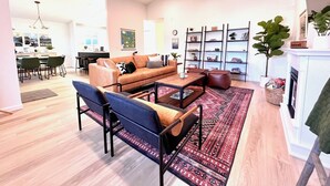 A modern living room with a sofa, coffee table, and chairs. There is a dining area in the background with a table and chairs. - Olympic House with SAUNA/Rec Room/AC in the Heart of Port Angeles (Port Angeles)