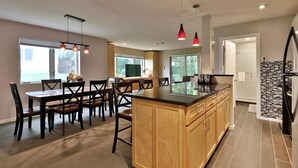 Une cuisine moderne avec des meubles en bois, un îlot central et des suspensions rouges.