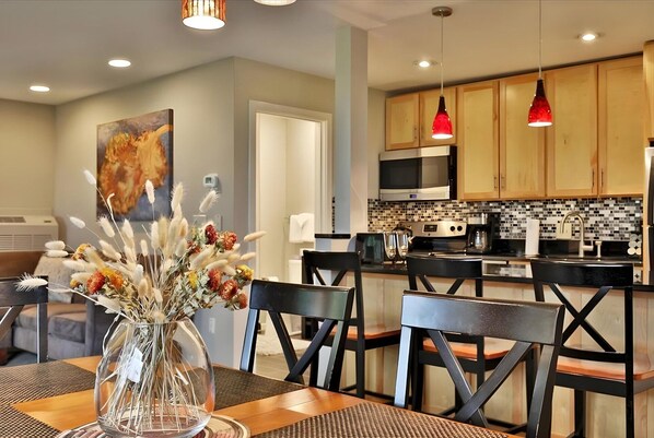 A modern kitchen with wooden cabinets, a black countertop, and a red pendant light.