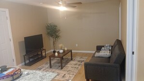 Un salon avec un téléviseur, un canapé, une table basse et une plante.