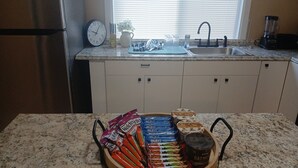 Une cuisine avec un plan de travail en granit, un évier, une horloge et des placards.