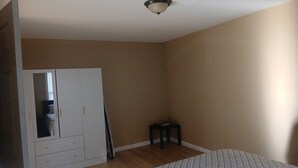 Une pièce avec une armoire blanche, une petite table et des murs de couleur beige.