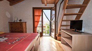 A bedroom with a bed, a wooden dresser, a television, and a large window. - Beautiful apartment for 3 people with WIFI, TV, patio and pets allowed (Era)