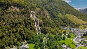 A mountainous landscape with a waterfall, a small village, and a prominent peak. - Beautiful apartment for 3 people with WIFI, TV, patio and pets allowed (Era)