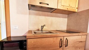 A compact kitchen with a built-in microwave, a sink, and wooden cabinetry. - Beautiful apartment for 3 people with WIFI, TV, patio and pets allowed (Era)