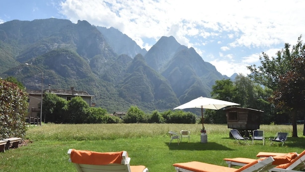 Uma área gramada com cadeiras de descanso e guarda-sol, com vista para uma paisagem montanhosa.