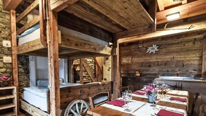 Ein rustikaler Holzraum mit einem Etagenbett, einem Esstisch für zwei Personen und einer Steinwand.