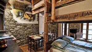 Ein rustikaler Raum mit Steinwand, Holzmöbeln, einem Bett und einem Schild mit der Aufschrift "CASEFICCI del PIAN 1848".