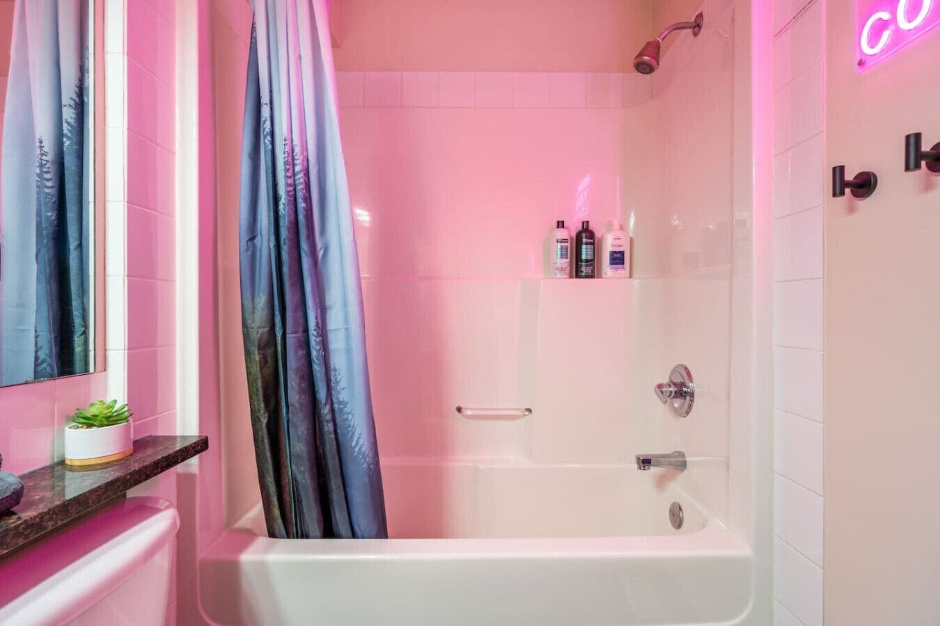 A modern bathroom with a white bathtub, a shower area, and a vanity with a mirror and a small plant.