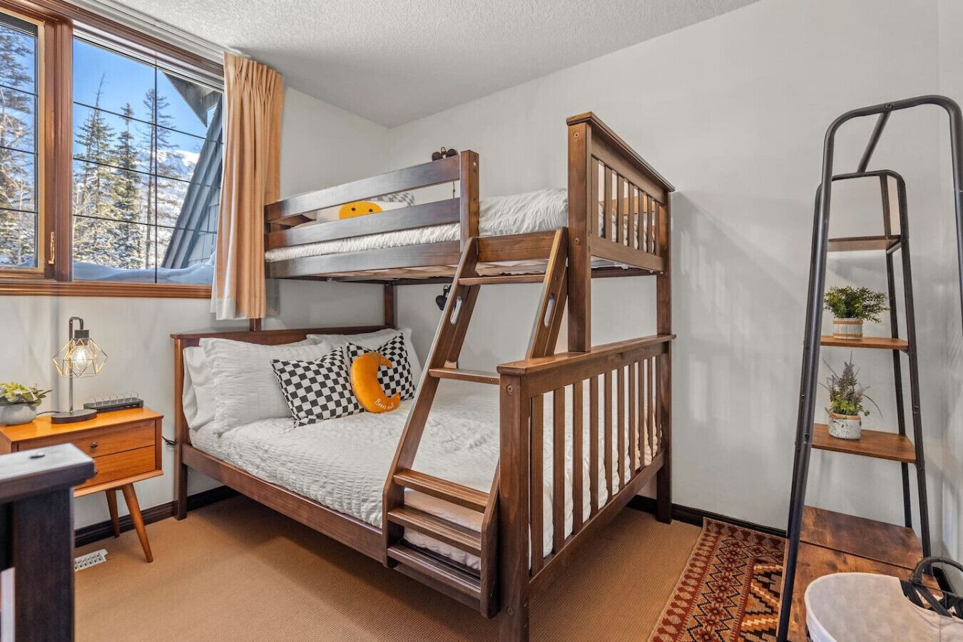 A bunk bed with a ladder, a desk with a lamp, and a plant shelf.