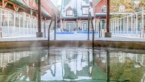Una piscina interior con agua cristalina, rodeada de muros de piedra y vigas de madera.