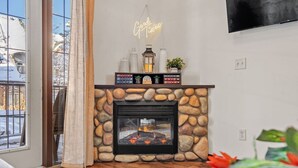 Una sala de estar acogedora con chimenea de piedra, una estantería y un letrero de neón.