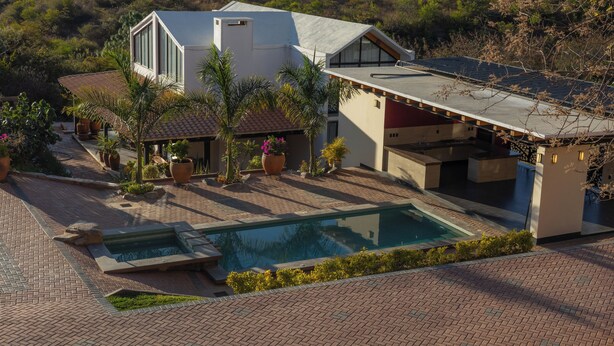 Une maison moderne dotée d’une piscine, d’un espace salon extérieur et d’un jardin.