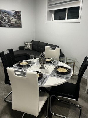 Een eetruimte met een ronde tafel gedekt voor vier personen, omringd door zwart-wit stoelen.