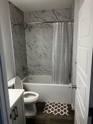 Een badkamer met toilet, bad en douchegordijn.