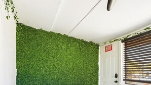 A spa area with a hot tub, artificial grass, an exit door, and a window with blinds.