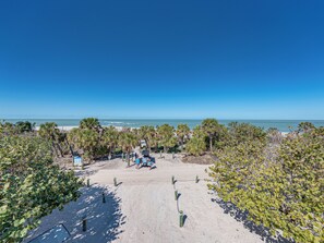 Vista de una playa con palmeras, arena y cielo azul despejado.