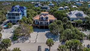 A beachfront property with multiple buildings, a large central house with a red roof, and a swimming pool.