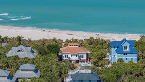 A coastal property with a beach view, multiple houses, and a swimming pool.