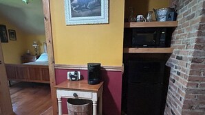 A kitchen with a microwave, a small wooden table with a coffee maker, and a brick wall.