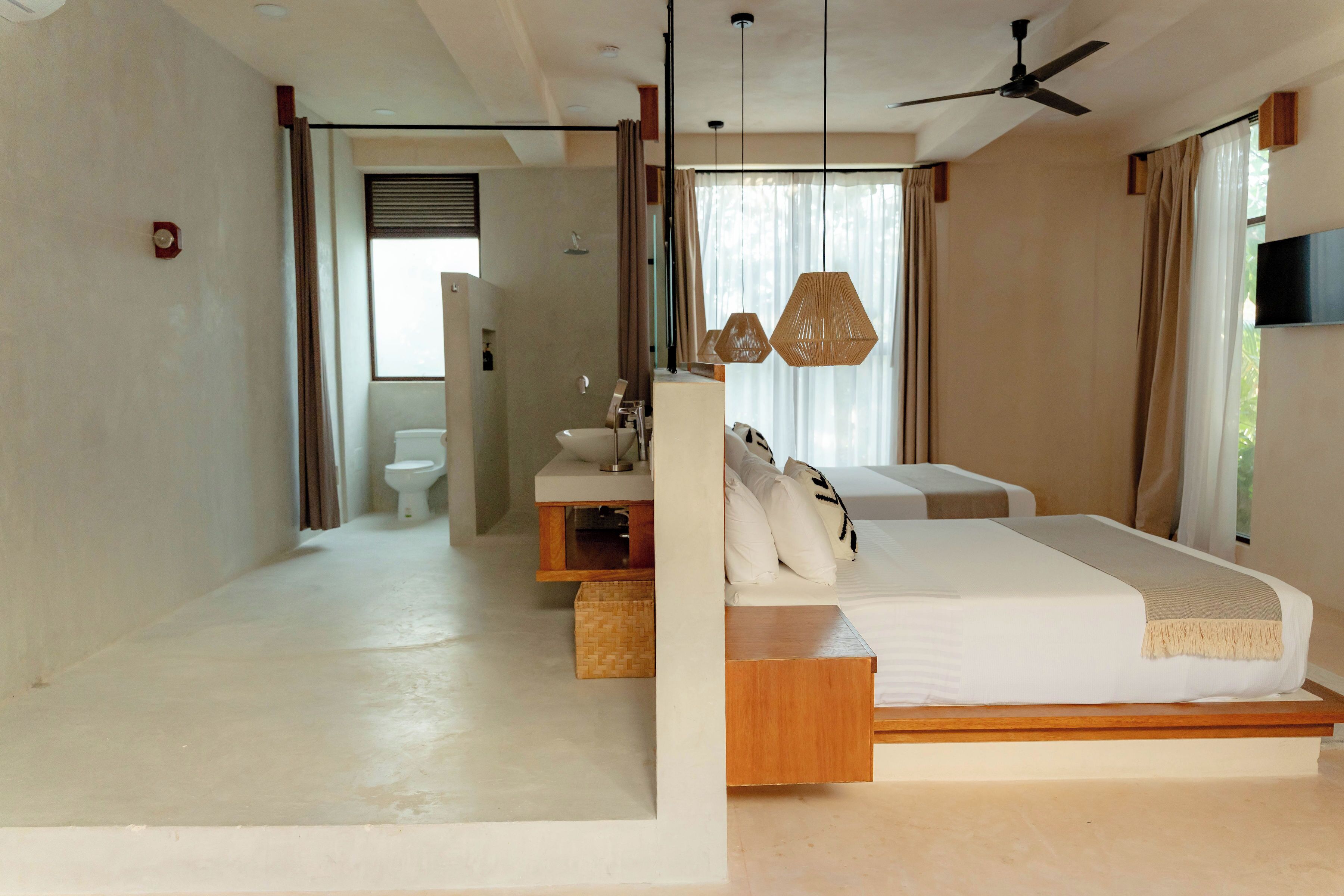 Un dormitorio moderno con una cama grande, mesitas de noche, un tocador y un ventilador de techo.