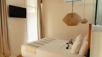 Een slaapkamer met een bed, een wandtelevisie, een airconditioning en een raam met gordijnen.
