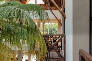 A wooden deck with a thatched roof, surrounded by lush greenery. - Hotel Joanza Holbox (Isla Holbox)