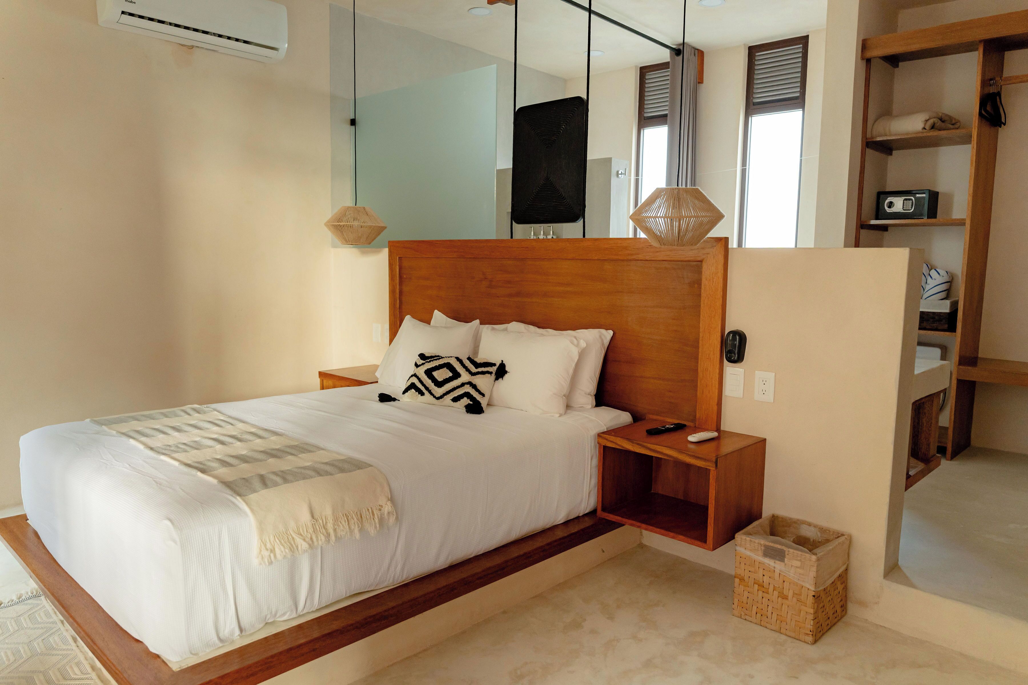 A modern bedroom with a wooden bed frame, white bedding, and a bedside table with a remote control.