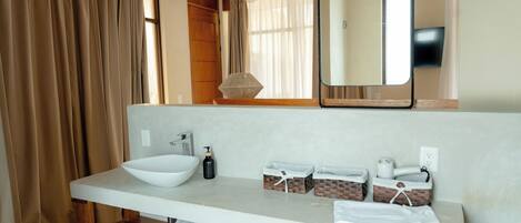 A modern bathroom with a large mirror, a white sink, and wooden shelves.
