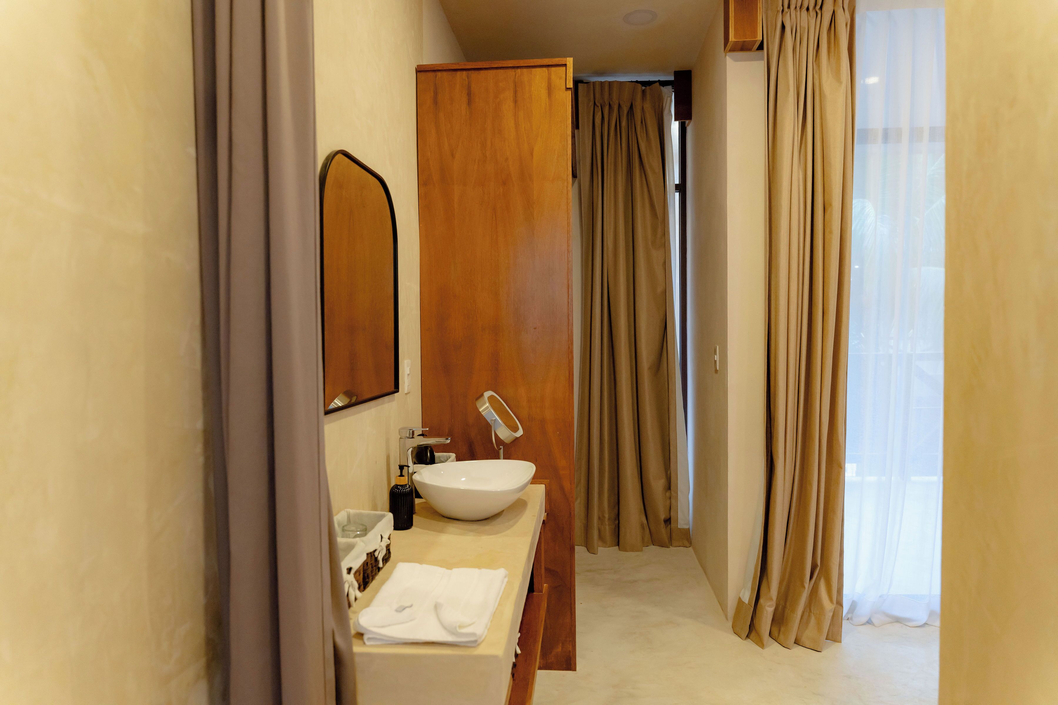 A hotel bathroom with a sink, mirror, and towel.