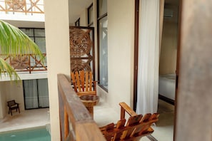 A balcony with a wooden chair, a small table, and a wicker chair. - Hotel Joanza Holbox (Isla Holbox)