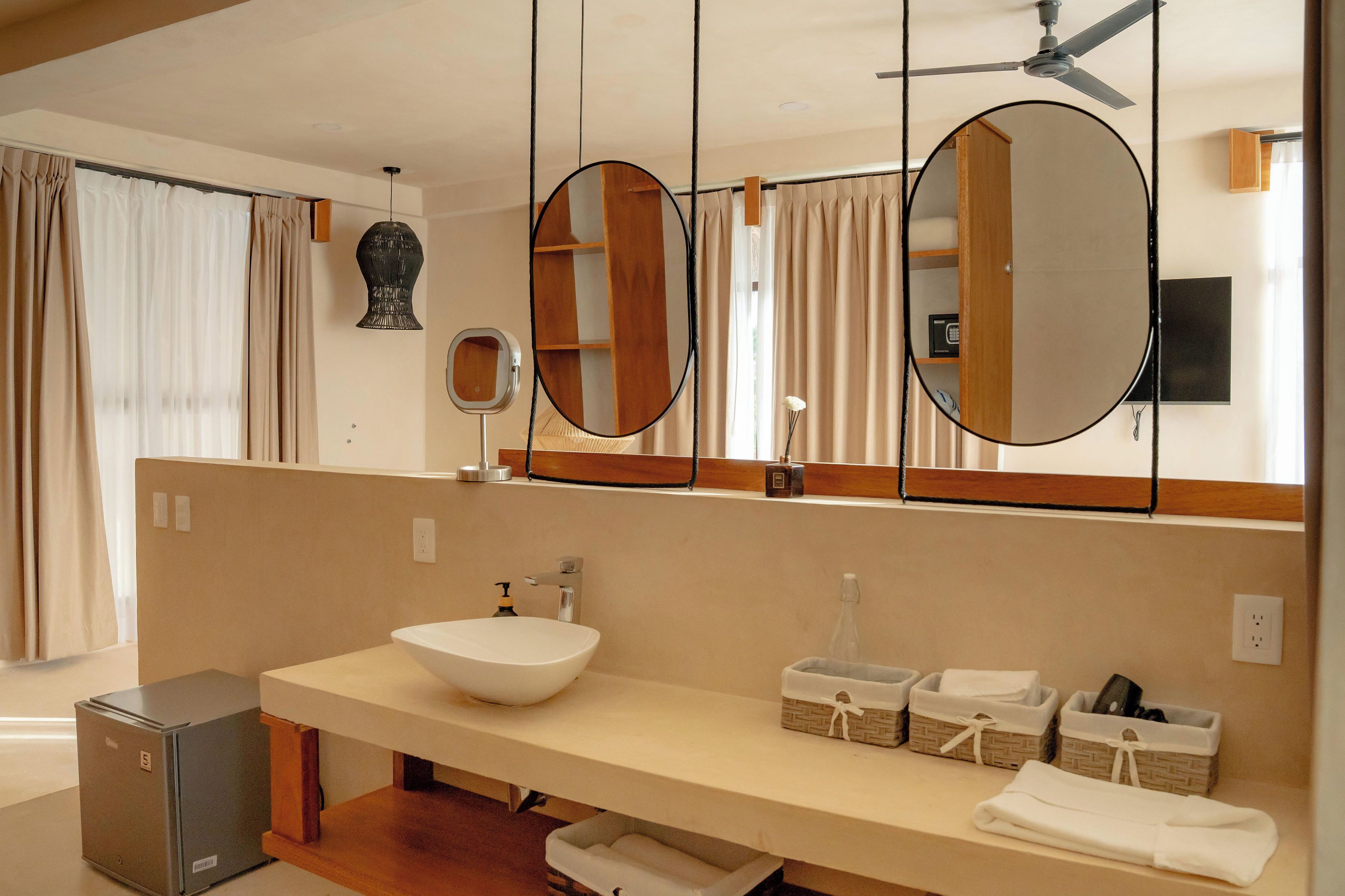 Un baño moderno con un espejo grande, un lavamanos y un ventilador de techo.