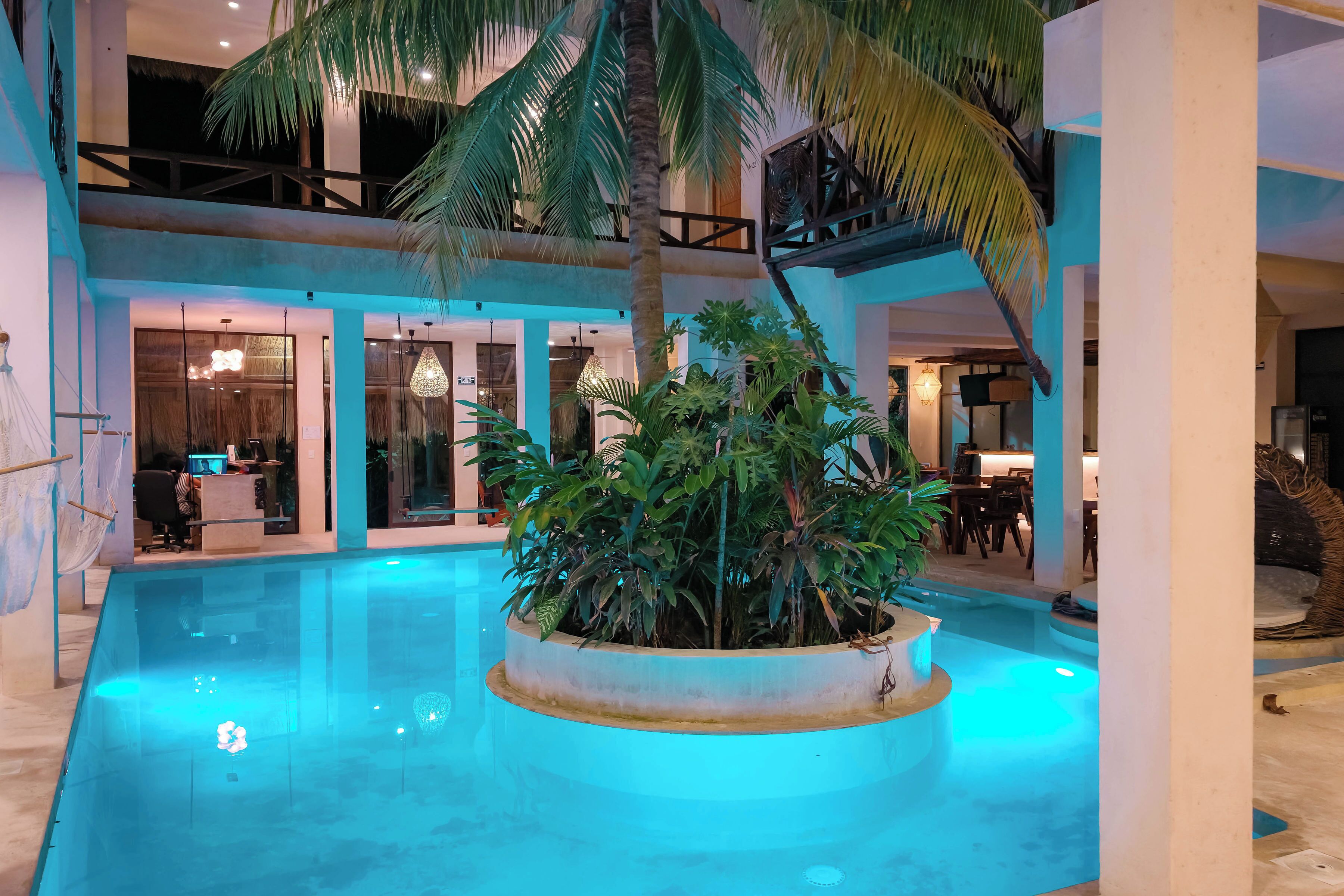 Un espace piscine agrémenté d’un jardinière centrale, d’un coin salon intérieur et d’un espace repas.