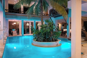 Uma área de piscina com um canteiro central, assentos internos e um espaço para refeições.