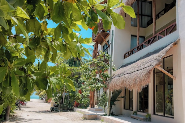 Un hotel con techo de paja, ventanas amplias y vista al mar.