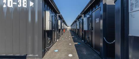 A row of shipping containers with numbers 20-38 visible, arranged in a linear fashion with a clear path between them.